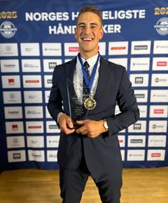 Dag Olav Håkedal står smilende foran en sponsorvegg med pokal i hånda.