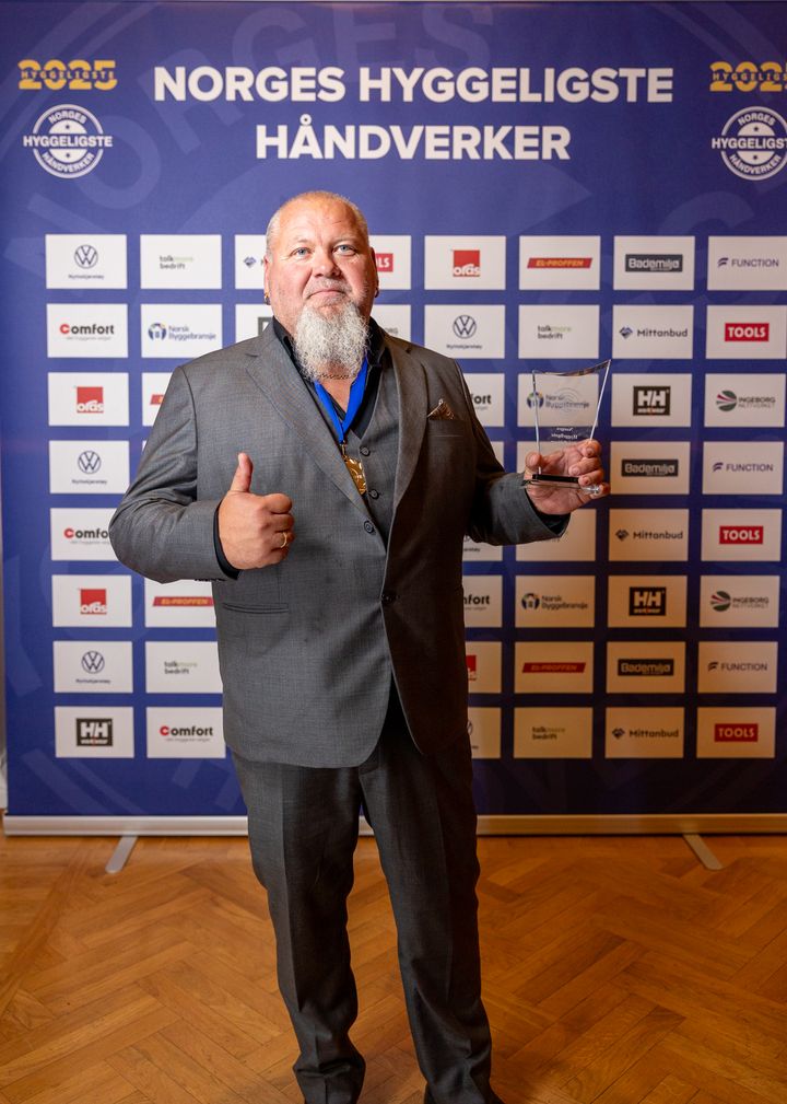Gothard Høyen Østerhaug står foran sponsorveggen med pokal i hånda.