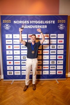 Hilmar Iversen står foran sponsorveggen under kåringen av Norges Hyggeligste Håndverker 2025.