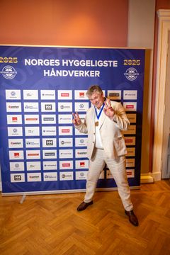 Terje Norheim står foran sponsorveggen og viser peace-tegn.