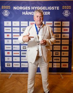 Terje Norheim står foran sponsorveggen med pokalen i hånda.