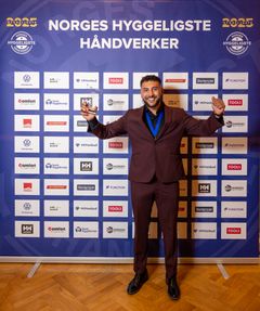 Sajjad Youssefi feirer seieren foran sponsorveggen under kåringen av Norges Hyggeligste Håndverker.