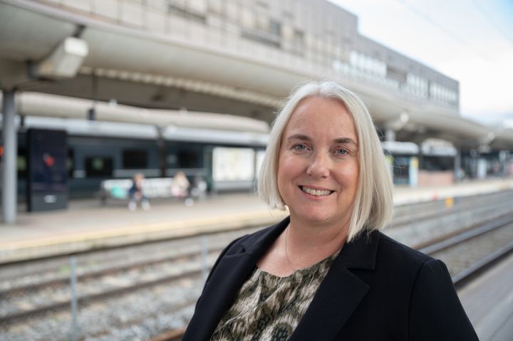 Marit Rønning er ny fungerende jernbanedirektør frem til en permanent direktør er rekruttert. Rønning poserer på Oslo sentralbanestasjon på perrongen foran jernbanesporene.