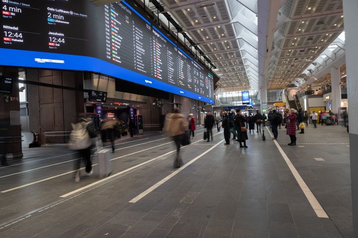 Rutetavlen på Oslo S, flere passasjerer i bevegelse.