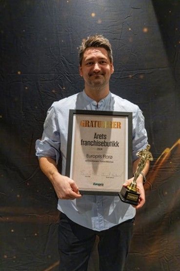 Fornøyd butikksjef og franchisetaker, Thomas Mikkelsen, med statuett og diplom.