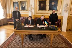 Stortingspresident Masud Gharahkhani og Ukrainas parlamentsformann Ruslan Stefantsjuk sitter ved et bord i Eidsvollsgalleriet i Stortinget og signerer hvert sitt eksemplar av en avtale om demokratisamarbeid.