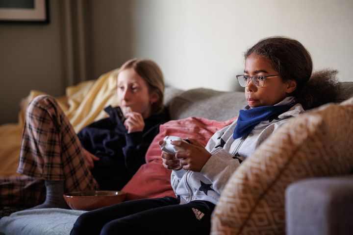 To jenter sitter i en sofa og spiller videospill