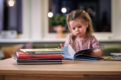 Et barn sitter og leser ved et bord. I forgrunnen ses barnebøker.