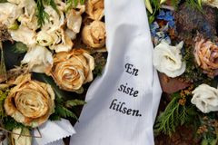 Visne blomster, roser med sørgebånd på grav.