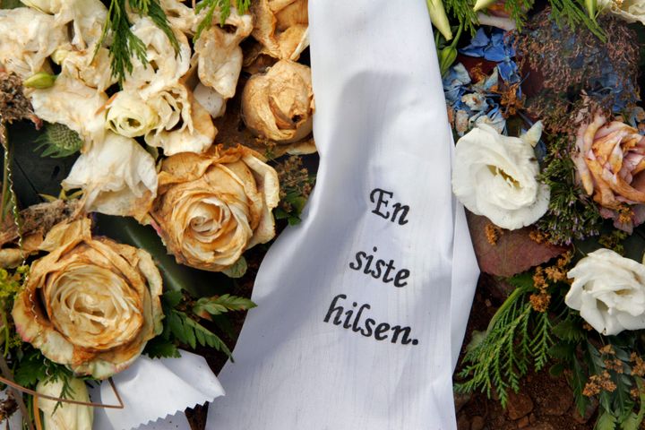Visne blomster, roser med sørgebånd på grav.