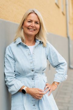 Bilde av smilende kvinne med lyst hår og blå kjole, som jobber som seniorrådgiver hos Akan kompetansesenter