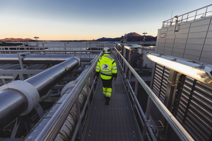 Person i Gassco verneklær på Nyhamna prosessanlegg i soloppgang.