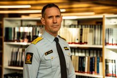 Mann i politiuniform står foran bøker i biblioteket