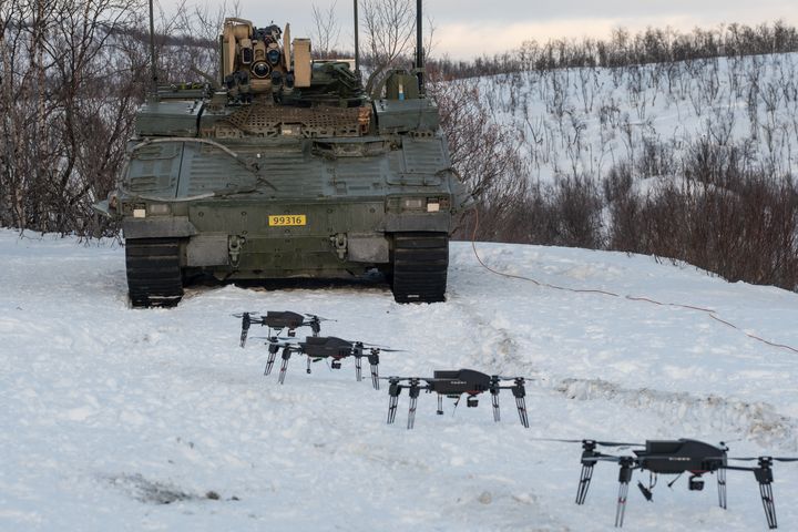 En panservogn og fire droner. Utendørs. Vinter. Nordnorsk landskap.