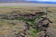 Oversiktsbilde av tundra som sprekker opp på Svalbard. Fjell i horisonten.