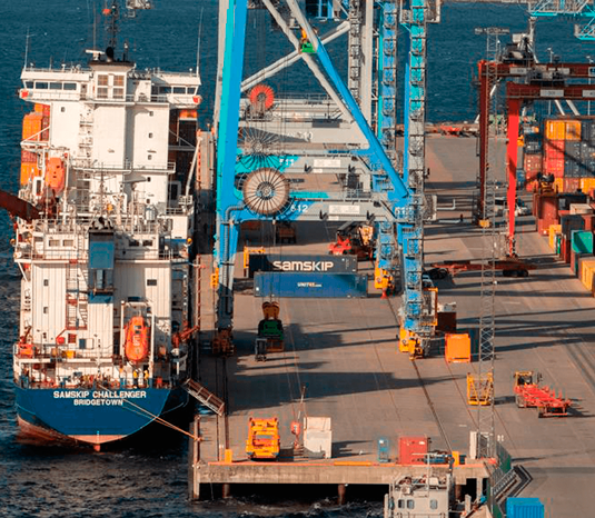 Illustrasjonsfoto: Contaninerskip ligger til kai for lossing og lasting. På kaia er stor kran, mange containere, transportkjøretøy