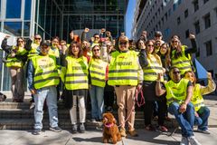 En gruppe streikevakter i refleksvester står samlet utendørs med armer hevet i solidaritet.