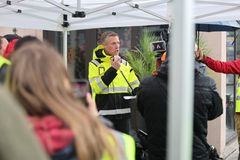 En person i gul refleksjakke holder en tale under en støttemarkering.