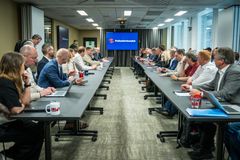 Alt text: Mange personer sitter rundt et langt forhandlingsbord i et møte om bussbransjeavtalen. En skjerm i bakgrunnen viser Fellesforbundets logo.