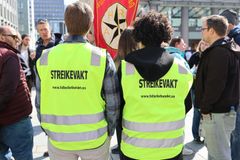 To personer med gule vester som det står "streikevakt" på, står i en folkemengde.