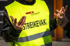 En person iført gul vest med teksten "Streikevakt" fra Fellesforbundet. Hendene gestikulerer.