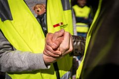 En nærbilde av to personer som håndhilser, iført gule refleksvester.