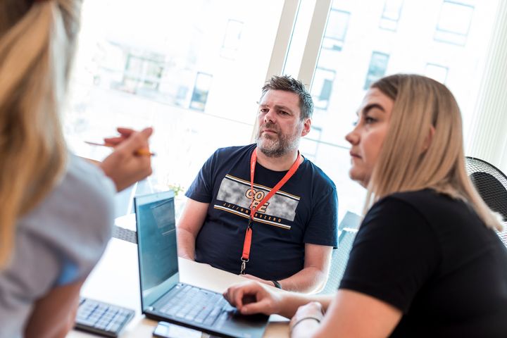 To kvinner og en mann sitter rundt et bord.