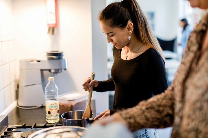 Ung tenåringsjente lager mat ved siden av en voksen