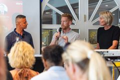 En paneldiskusjon med tre personer som snakker foran et publikum.