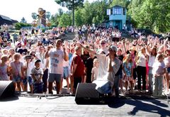Artist på scenen med et entusiastisk publikum under en utendørs konsert.