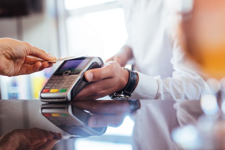 En person som betaler med et kredittkort ved å holde kortet sitt til en betalingsterminal.