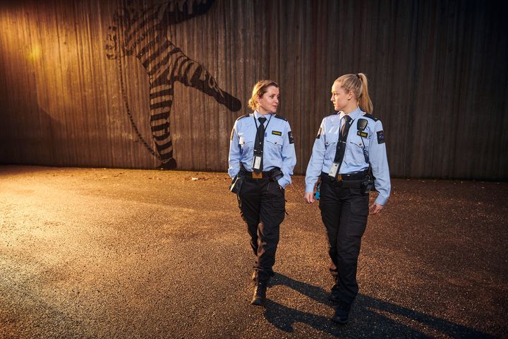 To kvinnelige fengselsbetjenter i uniform går over et område innenfor fengselsmuren