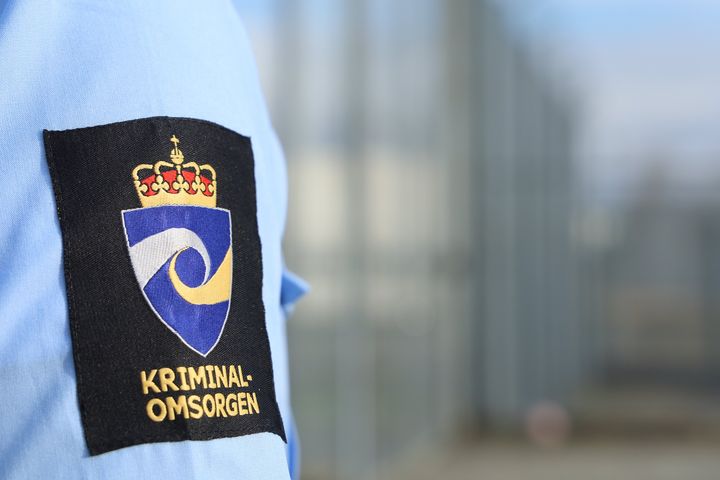 Skjorteerme med kriminalomsorgens logo på overarmen