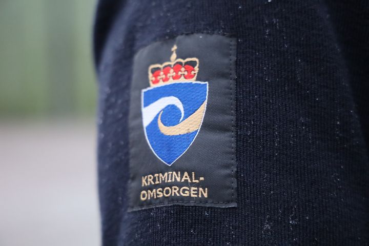 Fengselsbetjentgenser med kriminalomsorgens emblem på skulderen