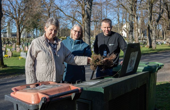 bilde av tre personer som putter avfall i en avfallsdunk på en kirkegård.