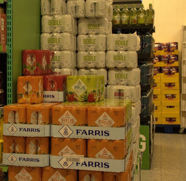 Bildet viser stabler med brusbokser som er pakket inn i plast.