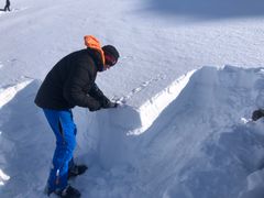 En mann står vendt mot en snøskavel med et skjæreverktøy.