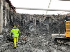 Mann i arbeidsklær står nede i en byggegrop.