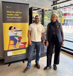 To personer står foran en reklameplakat.