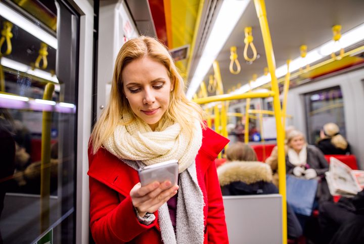 En kvinnelig passasjer på en t-bane holder en mobiltelefon