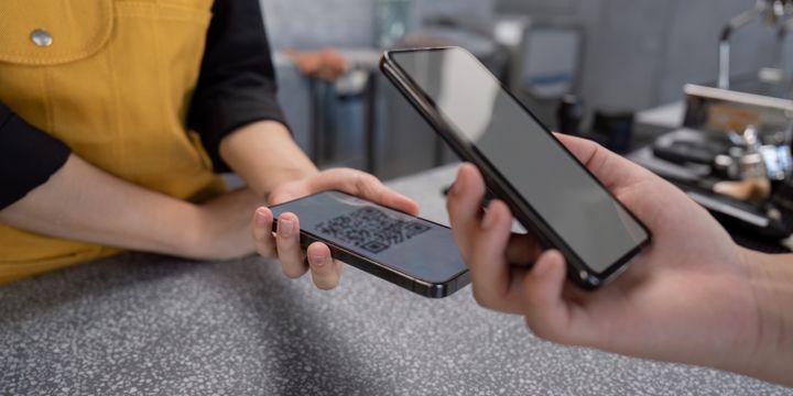 To personer holder hver sin mobiltelefon mot hverandre for å dele data.