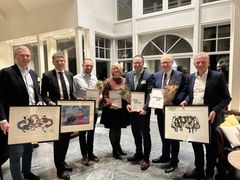 Syv personer smiler og viser fram bilder og diplom