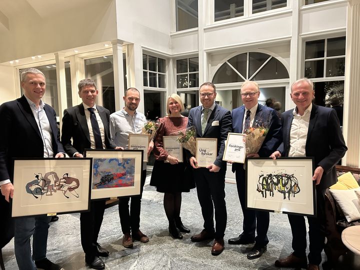 Syv personer smiler og viser fram bilder og diplom