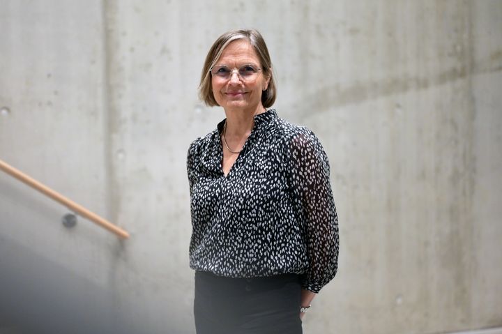 Dame står ved en trapp og smiler til kamera