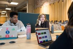 En gruppe studenter som sitter med laptopen åpen og prater sammen.