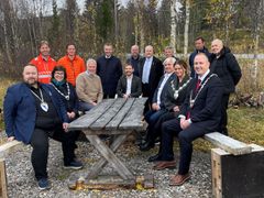 Historisk svung: Med stor entusiasme benket politikere, entreprenører og vegvesenets ledere seg i dag rundt et grovt snekret trebord på Helgeland, for å gjenskape en av landets viktigste vegåpninger 100 år etter. Rundt bordet fremme fra venstre: Raymond Fagerli, ordfører i Grane (Sp), Sølvi Andersen, ordfører i Hattfjelldal (AP), Ove Myrvåg, assisterende vegdirektør Statens vegvesen, Tom Kalsås, statssekretær i Samferdselsdepartementet (Ap), Videre mot venstre på benken: Kjell Inge Davik, Utbyggingsdirektør Statens vegvesen, Ann Jeanett Klinkenberg, ordfører i Grong (Ap), Rune Krutå, ordfører i Vefsn (Ap) Bak fra venstre: Harald Inge Johnsen, prosjektleder E6 Grong-Nordland grense (Statens vegvesen). Frank Syltern, prosjektleder Johs J Syltern (Hovedentreprenør på E6 Trøndelag grense-Lille Majavatn). Tomas Iver Hallem, fylkesordfører i Trøndelag (Sp), David Letnes, daglig leder Letnes Entreprenør AS, (Hovedentreprenør E6 Fjerdingen-Grøndalselv) Bjørn Larsen, fylkesråd for næring Nordland (Frp), Bjørnar Selnes Skjæran stortingsrepresentant for Nordland Ap, Bjørn Tore Nordlund, kommunalsjef Namsskogan kommune. Paul Asphaug, ordfører i Hemnes (Sp)