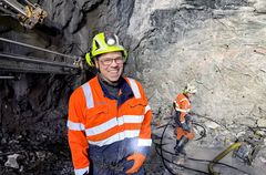 Bildet viser  sprengningsbas Tore Gunnar Gundersen med lærlig Trond Randen i bakgrunnen, som lader ferdig borede hull i fjellveggen (stuffen) og gjør klart til sprengning.