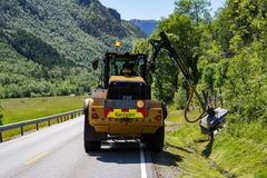 Bilde av traktor som slår sideområde ved veg.