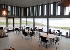 Kafe med utsikt til sandtrand og fjell.