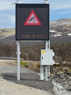 Digital skilttavle som viser vindpølse-symbol og tekst: Vind 19 m/s.